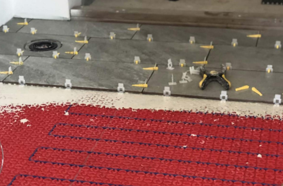 Underfloor radiant heating cable system being installed in a house.