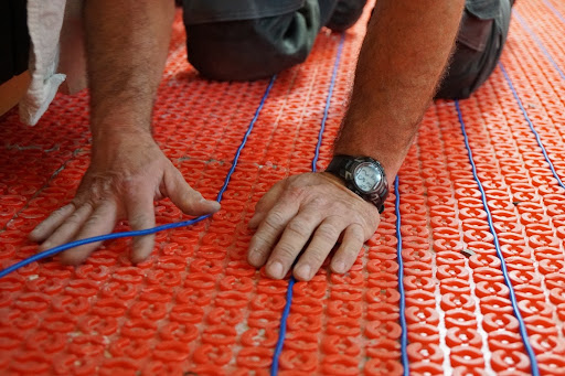 A man installing Warmup's DCM-PRO Underfloor Radiant Heating System.