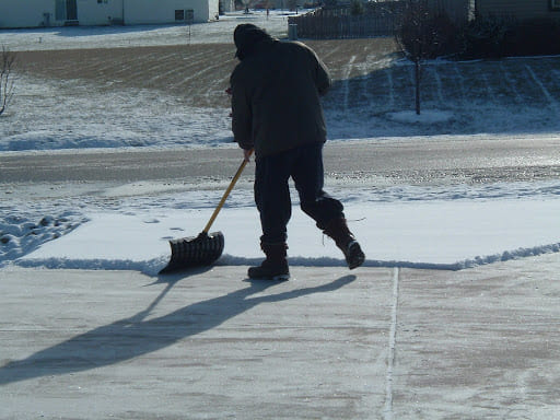Man shoveling snow in a driveway.